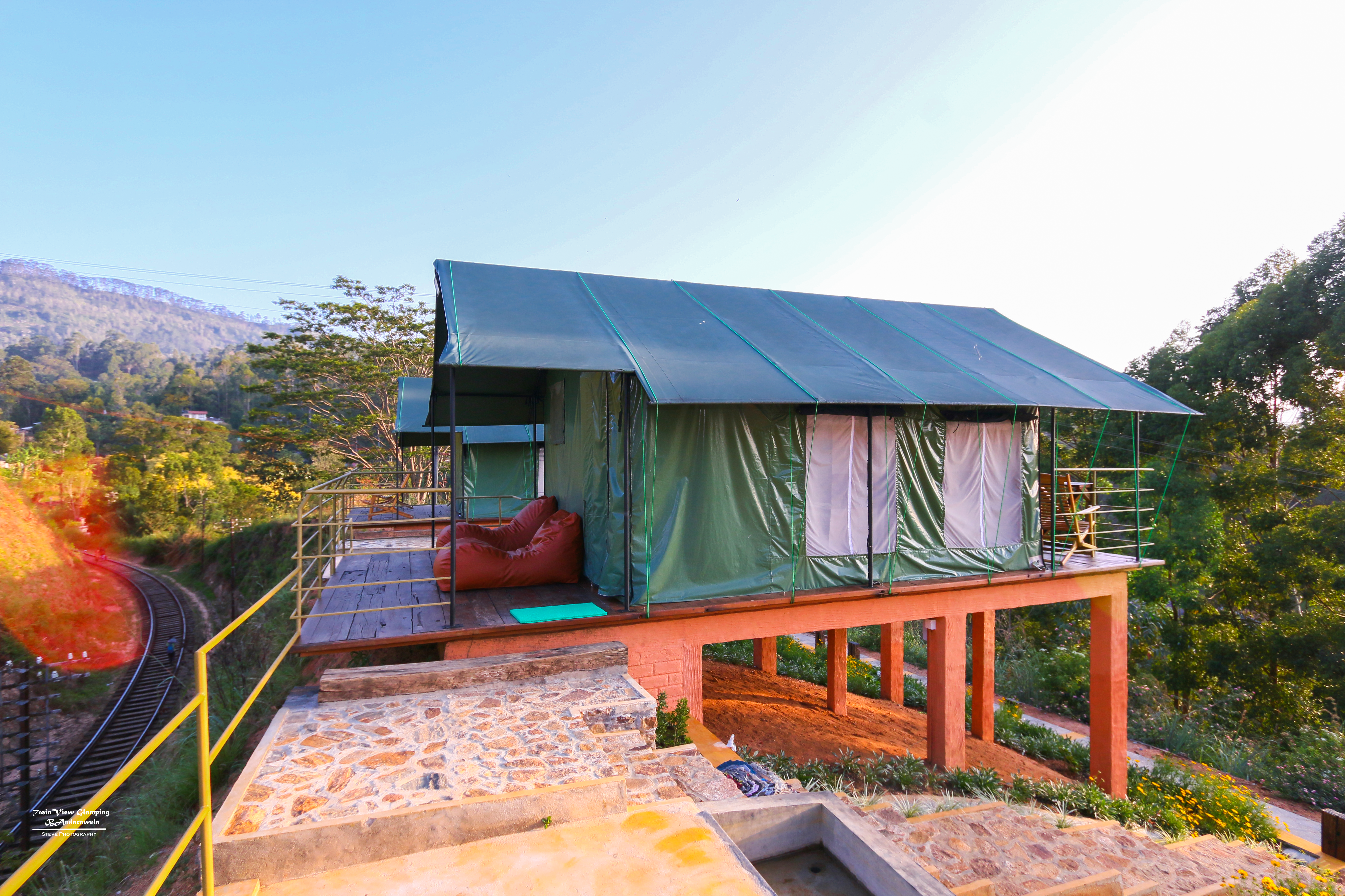Elevated green glamping tent beside the curving hill-country railway