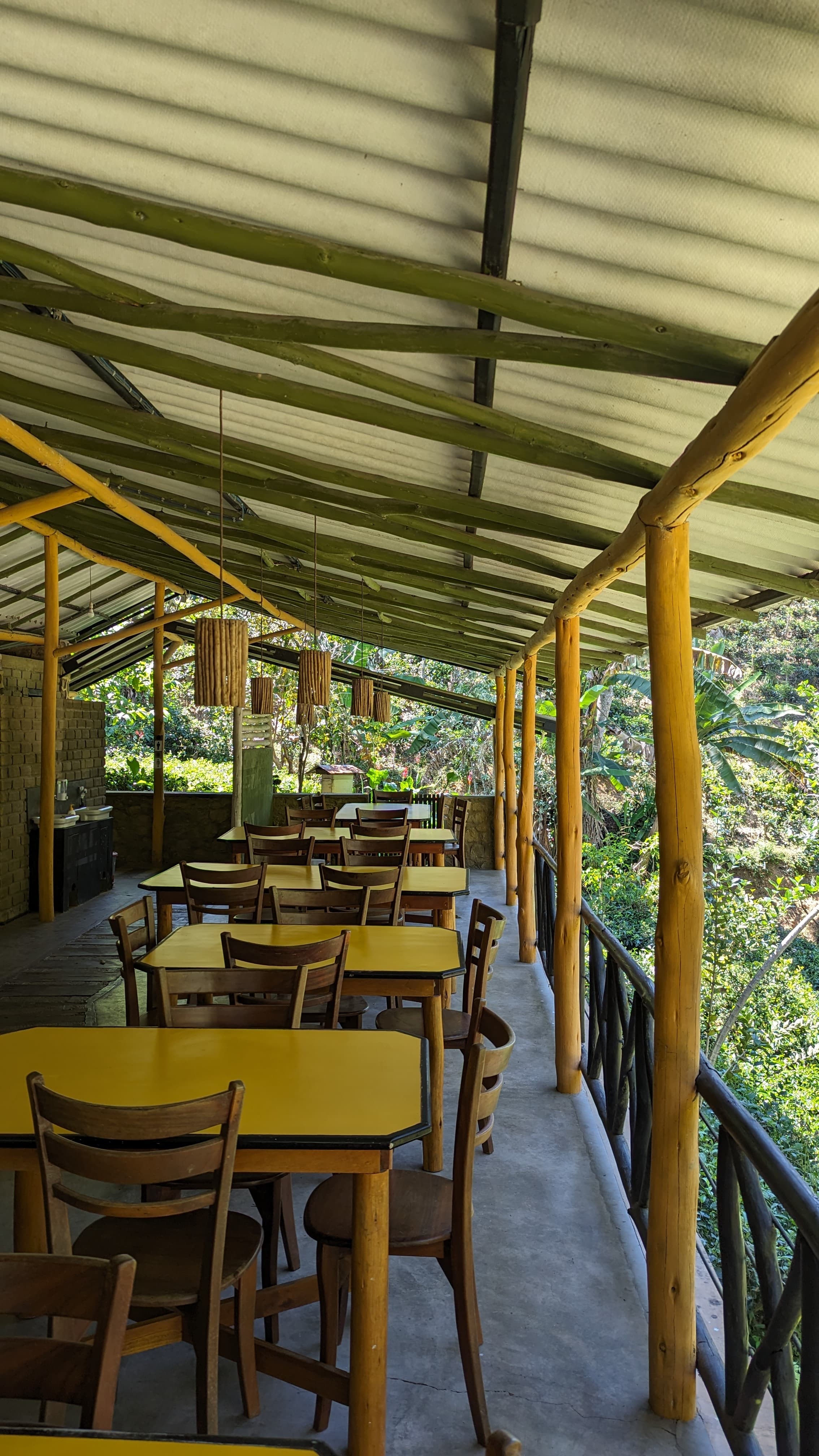 Tables arranged along the open-air restaurant overlooking greenery